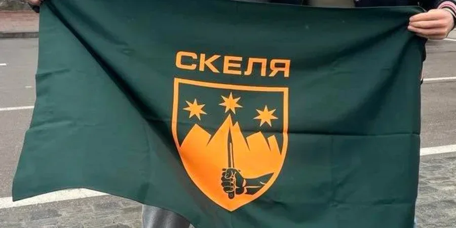 Людина тримає зелений прапор з емблемою полку Скеля
