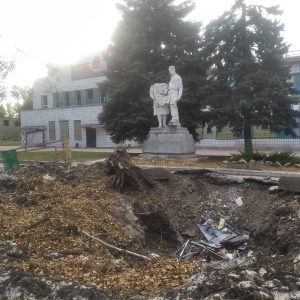 Статуя чоловіка з дитиною на тлі розритої ями та сміття в окупованому Криму