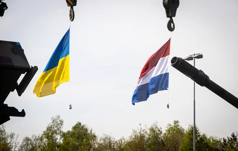 Прапори України та Нідерландів на тлі стволів військової техніки