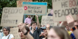Молодий чоловік тримає плакат FATAL ERROR Minister not found серед протестувальників
