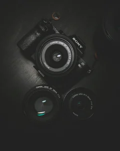 Чорна камера Sony з трьома обєктивами Canon на темному столі