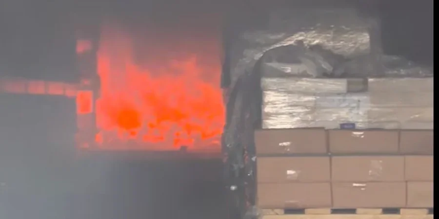 Яскрава пожежа в диму біля стосів коробок на складі