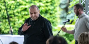 Рустем Умєров у чорній сорочці жестикулює рукою під час виступу просто неба