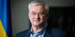 Портрет чоловіка з сивим волоссям в окулярах біля українського прапора