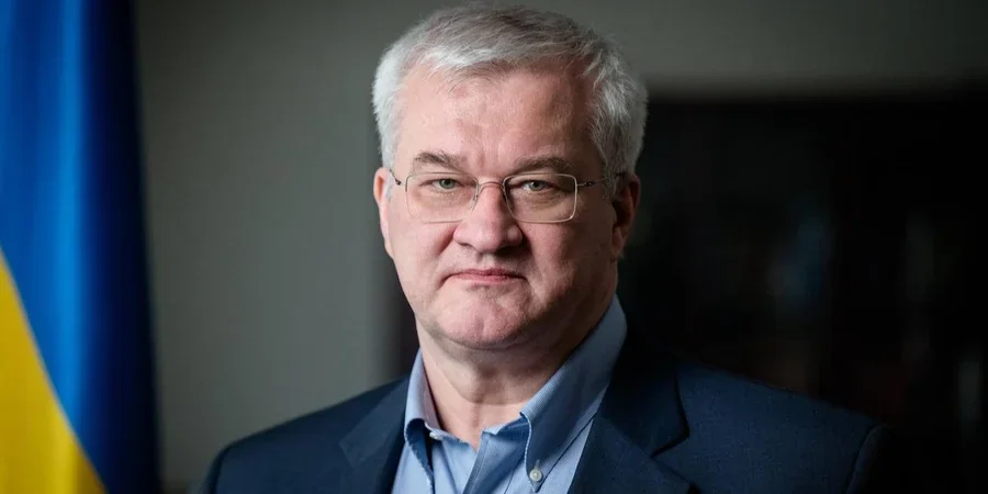 Портрет чоловіка з сивим волоссям в окулярах біля українського прапора